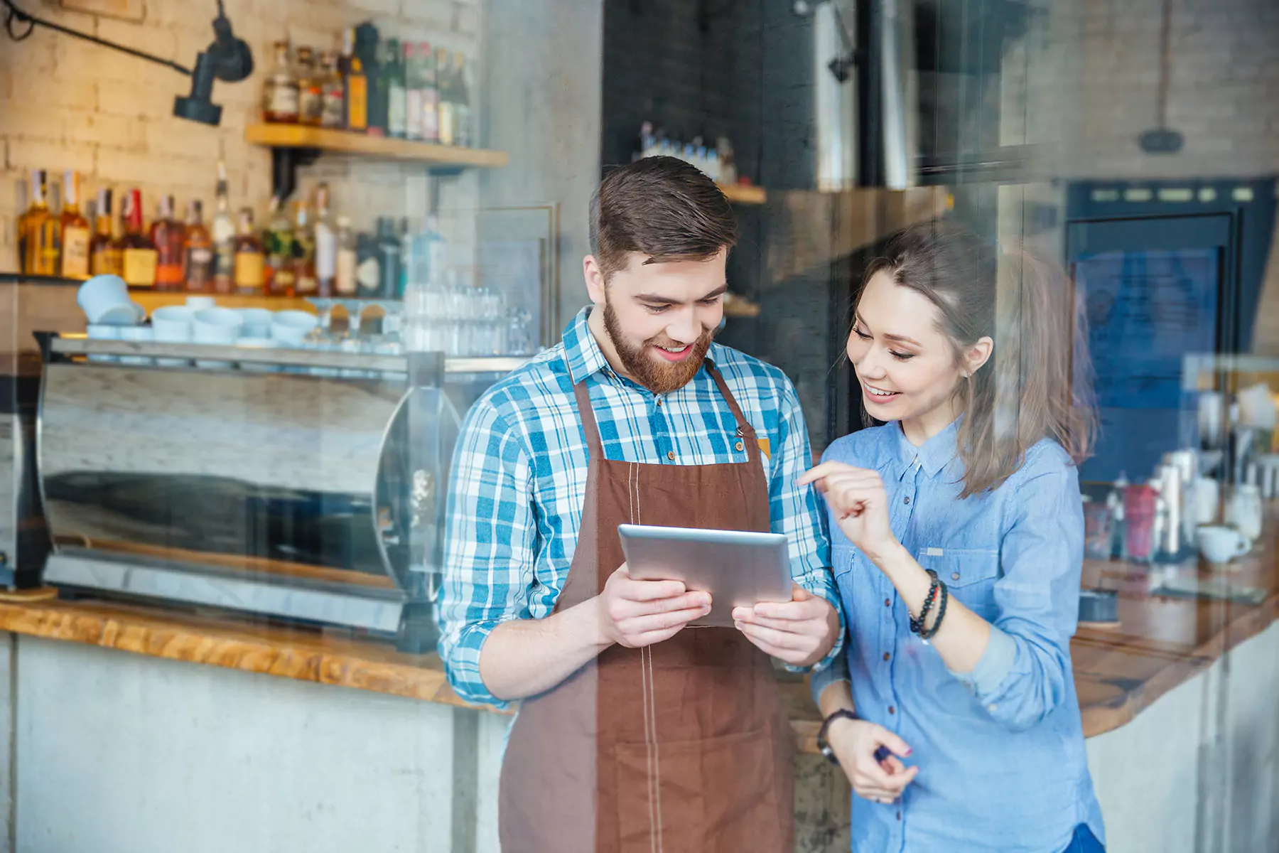 A woman and a waiter looking at the tablet
